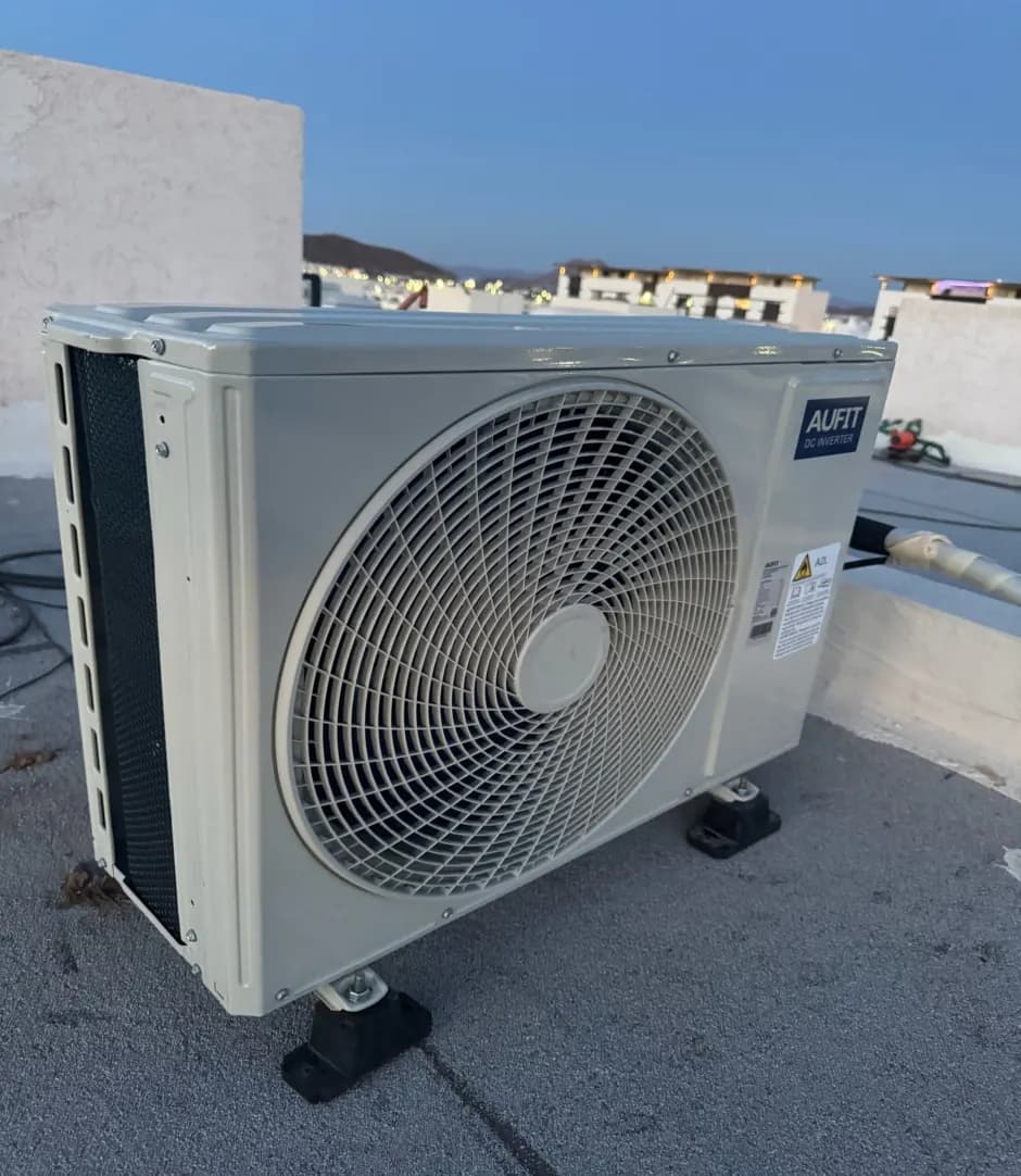 Unidad condensadora de minisplit instalada sobre bases antivibración en azotea residencial