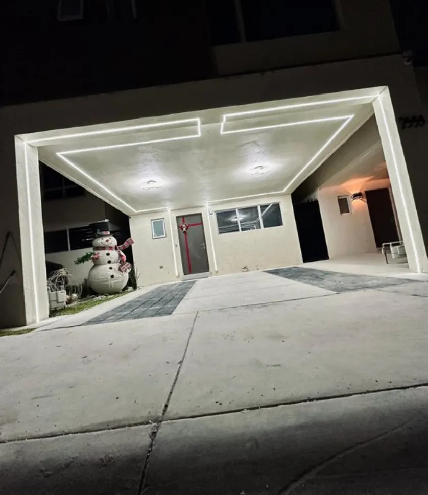 Cochera residencial de noche con líneas de luz LED blanca empotradas en el plafón
