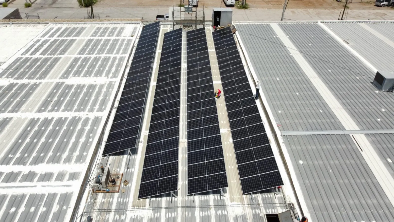 Vista aérea de largas hileras de paneles solares sobre techo de nave industrial