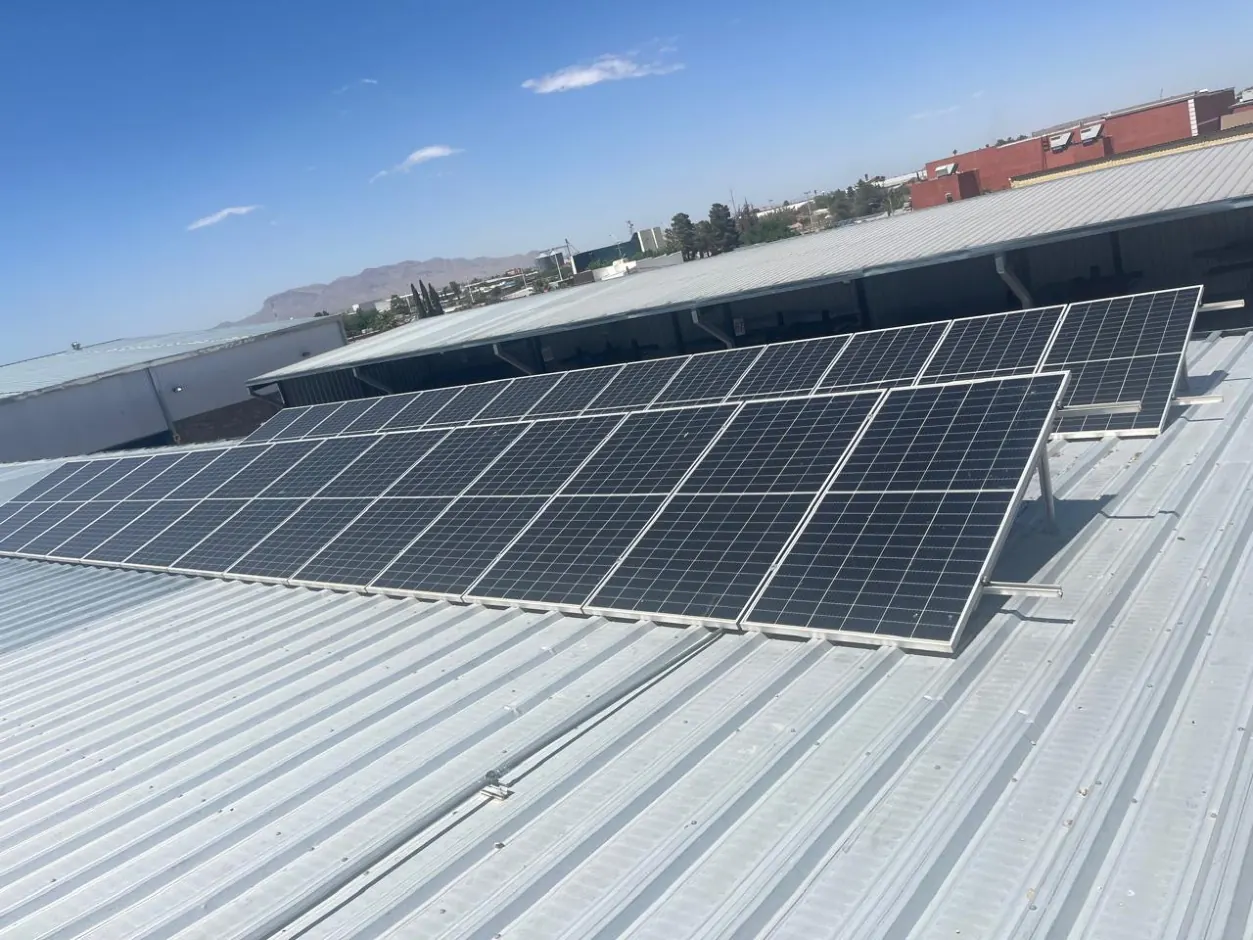 Paneles solares inclinados sobre techo de lámina de edificio industrial bajo cielo azul